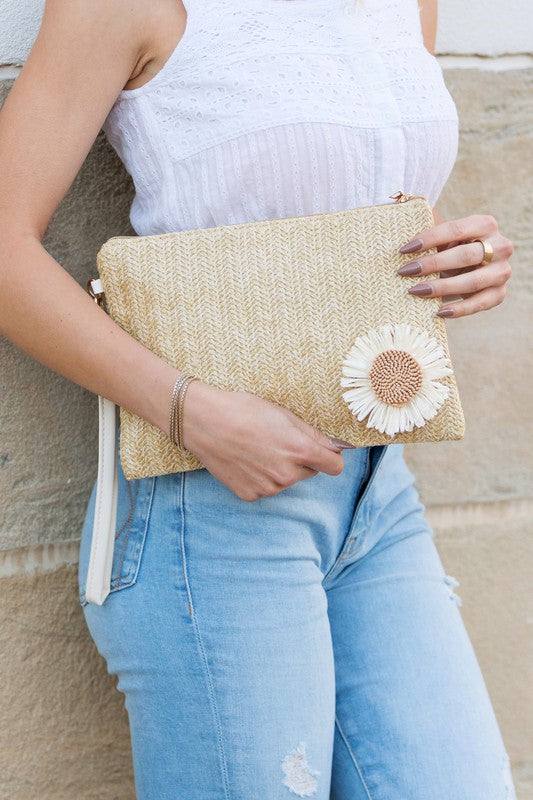 Daisy Wristlet ClutchDaisy Wristlet ClutchWoven Exterior DetailMeasurement 10.5" x 7.25"Removable Vegan Leather WristletPolyester LiningOpen InteriorExterior Material: StrawDaisy Embelli