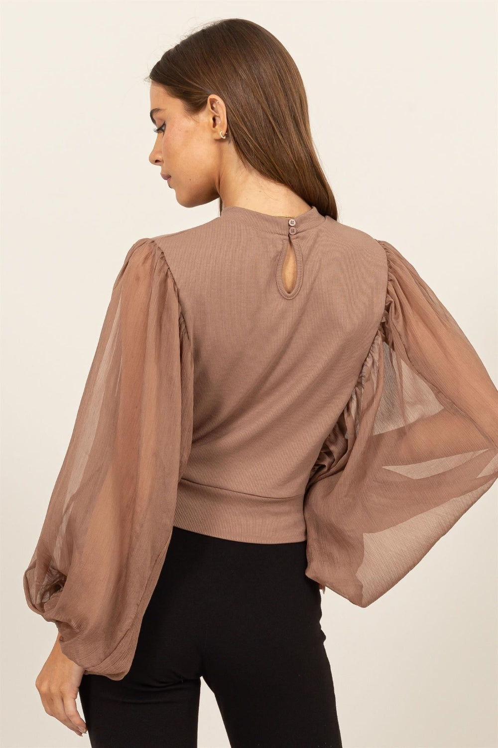 HYFVE Ruched Sheer Long Sleeve Mock Neck BlouseAugment your wardrobe's elegance with this Sheer Sleeve Back Button Blouse. Showcasing delicate sheer sleeves and a sophisticated back button closure, this blouse is