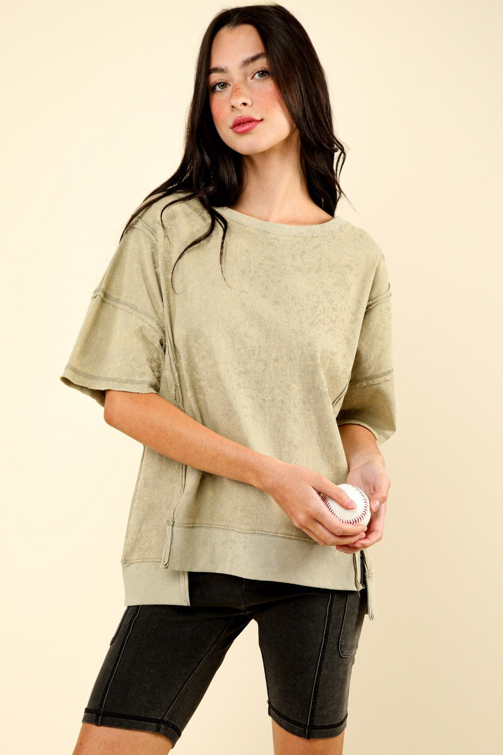 VERY J Round Neck Exposed Seam Slit T-ShirtElevate your casual wardrobe with this round neck exposed seam slit t-shirt featuring a stylish high-low hem design. The exposed seams add a trendy touch, while the 