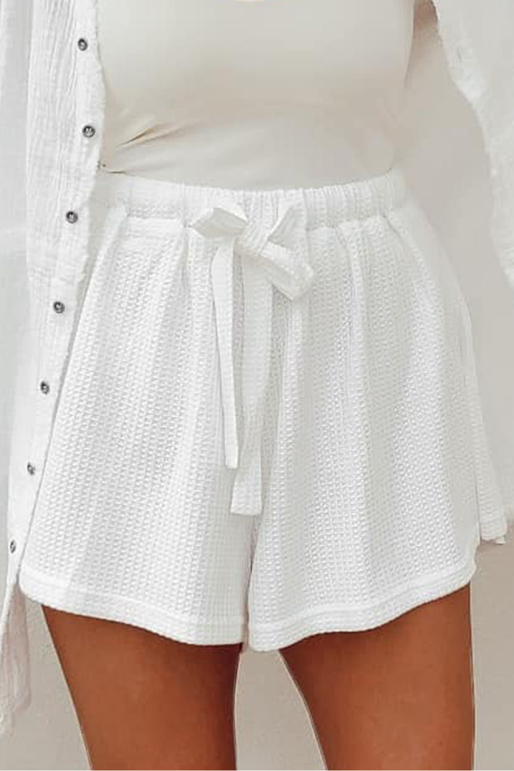 White Waffle Knit Lace-up High Waist Wide Leg ShortsMaterial:75％Polyester+20％Viscose+5％Elastane



		This pair of solid-color casual shorts is an essential piece to complete your outfit
	
	
		It features an elast